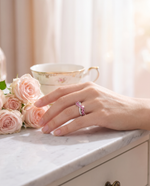 Lifestyle shot of model wearing pink tourmaline ring with roses in soft morning light