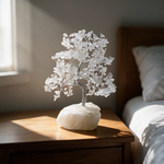 Clear quartz crystal tree on a bedside table in soft morning light