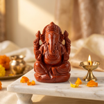 Red Jasper Ganesha in pooja corner with brass diya and marigold